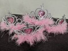 two tiaras with pink feathers and hearts on them