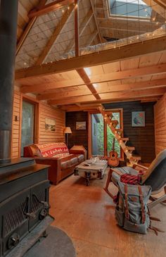 a living room filled with furniture and a wood burning stove top oven in front of a wooden wall