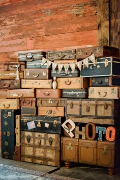 many suitcases are stacked on top of each other in front of a wooden wall