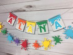 the word atlanta spelled out with colorful paint splatters on a white wooden background