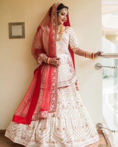 a woman in a white and red bridal gown posing for the camera with her hands on her hips