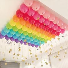 a bunch of balloons hanging from the ceiling in a room with stars on the wall