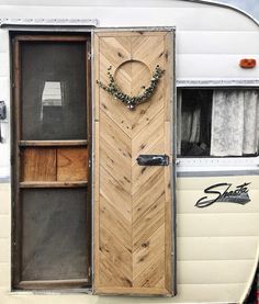 an old camper has a wooden door with a wreath on the front and side