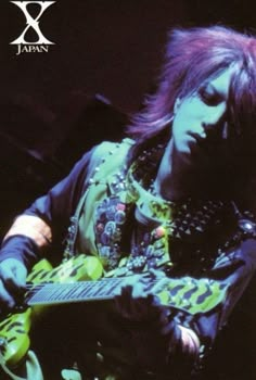 a woman with purple hair playing an electric guitar