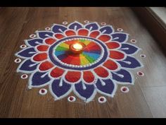 a candle is lit in the middle of a colorful flower design on a wooden floor