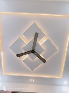 a clock mounted to the ceiling in a room with white walls and lights on it