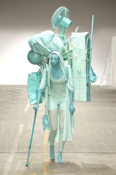 a woman walking down a runway with lots of blue items on her head and arms