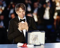 a man in a tuxedo and bow tie standing next to an open box