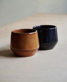 two black and brown bowls sitting on top of a table