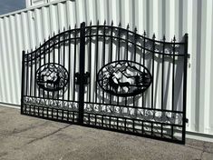 an iron gate with two circular designs on the top and bottom, in front of a white building