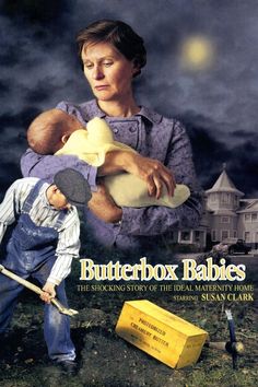 a woman holding a baby while standing next to a yellow box with a hammer in it