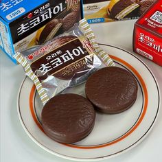 two chocolate cookies on a plate next to boxes of milk