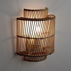 a light that is on the wall next to a wire basket with a lamp in it