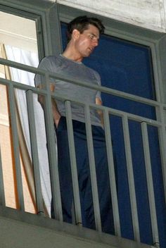 a man standing on top of a balcony next to a window