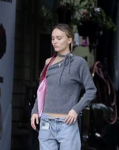 a young woman is standing in front of a building with her hands on her hips