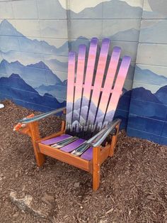 a wooden chair with skis on it sitting in front of a painted mountain scene