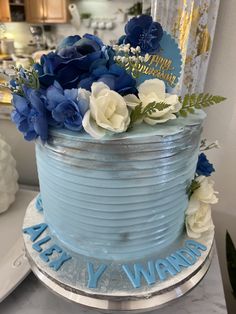 a blue cake with white and blue flowers on top