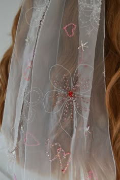 a veil with flowers and hearts on it is hanging from the back of a woman's head