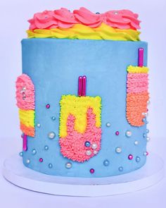 a blue cake with pink and yellow frosting on it's side, decorated with icing