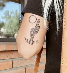 a woman's arm with a cactus and moon tattoo on the left side of her arm