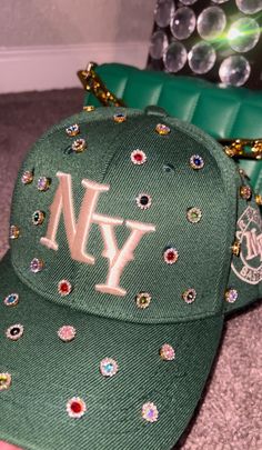 Adjustable NY Custom Bedazzled Hat customed by ShanayCosmetics Comes in 2 colors: Black or Green More colors COMING SOON....  PLEASE KEEP IN MIND THAT I AM NOT RESPONSIBLE FOR ANY DELAYS WITH SHIPPING ONCE I HAVE DROPPED YOUR PACKAGE OFF AT THE POST OFFICE! THAT IS OUT OF MY CONTROL. PLEASE BE AWARE I AM NOT RESPONSIBLE FOR ANY LOST, DAMAGED OR STOLEN PACKAGES!! Custom Ny Hat, Pearl Fitted Hat, Diy Leather Hat, Bedazzled Hat, Custom New Era Hats, Customized Hats, Bedazzled Stuff, Swag Items, Rhinestone Hat