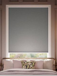 a bed sitting under a window covered in blinds