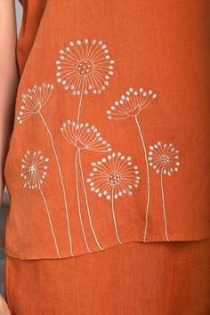 a woman is wearing an orange dress with white flowers on the front and back side