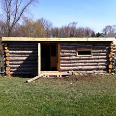 a log cabin with the door open and logs stacked on it's sides outside