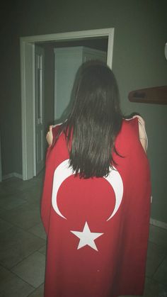 the back of a woman wearing a red shirt with a white crescent and star on it