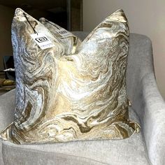 a silver and gold pillow sitting on top of a gray couch