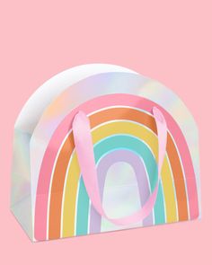 a paper bag with a rainbow design on the front and bottom, against a pink background