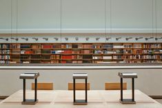 three metal benches sitting in front of a bookshelf