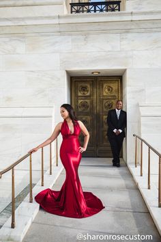 a woman in a red dress is walking down the stairs