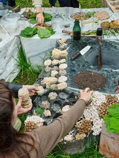 several people are gathered around a table with food and plants on it, including mushrooms