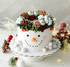 a cake decorated with flowers and snowmen on top of a white plate next to christmas decorations