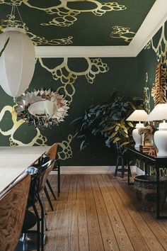 a dining room with green wallpaper and wooden flooring next to two lamps on either side of the table