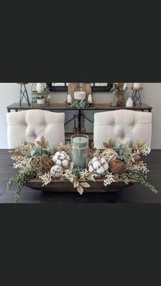 a dining room table with white chairs and greenery in the center, surrounded by candles