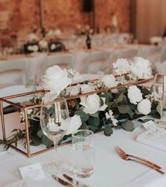 a table with white flowers and greenery on it is set up for a wedding reception