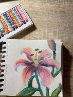 a watercolor painting of a pink flower next to some crayons