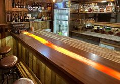 an empty bar with stools and bottles on the shelves in front of it,