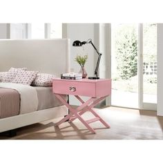 a bedroom with a bed, nightstand and pink table in the corner next to it