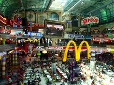 the interior of a mcdonald's restaurant with neon signs and advertisements on the ceiling