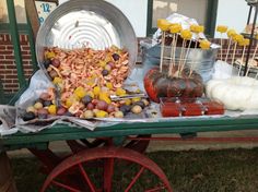 a table topped with lots of food on top of a green cart next to a brick building