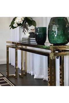 a green vase sitting on top of a glass table next to a white flower pot