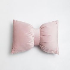 a pink pillow with a bow on it sitting on a white surface, top view