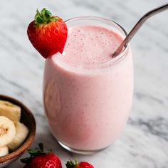 a smoothie with strawberries and bananas on the side