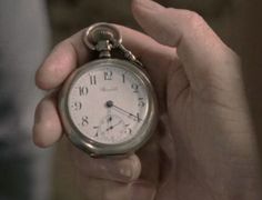 a person holding an old pocket watch in their hand with the time being 11 00