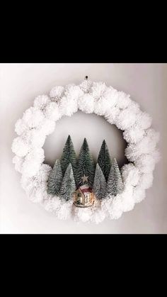 a christmas wreath with trees and a house in the middle is surrounded by fluffy white snow