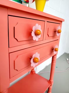 an orange dresser with flowers painted on it