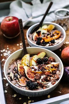 two bowls filled with oatmeal and fruit on top of a wooden table